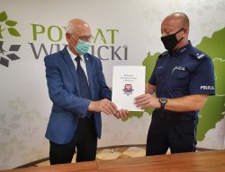 Starosta Wielicki oraz Komendant Powiatowy Policji w Wieliczce, trzymają w ręku podpisane porozumienie.