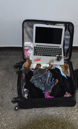 Czarna walizka, a w niej  laptop z logo firmy „apple” wraz z ładowarką, klucze ( w tym do pojazdu), ładowarka, torebka koloru brązowego, kosmetyki.
