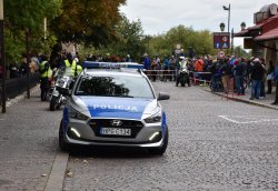 Radiowóz policyjny wykorzystany do zabezpieczenia wyścigu. W tle osoby obserwujące wyścig.