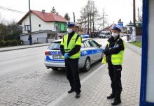 Policjant i policjantka stojący przy radiowozie.