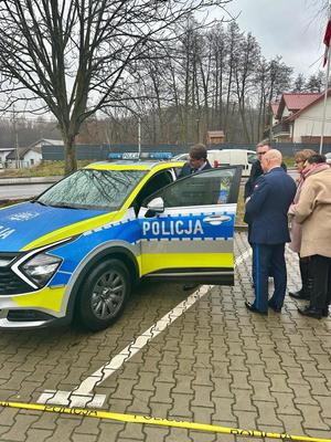 Starosta wielicki wsiadający do radiowozu. Obok Komendant KPP Wieliczka i samorządowcy