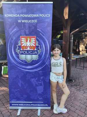 Uczestniczka pikniku przy banerze KPP Wieliczka