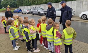 Przedszkolaki oraz policjanci stoją na chodniku