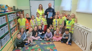 Wspołne zdjęcie przedszkolaków, wychowawczyni oraz policjanta