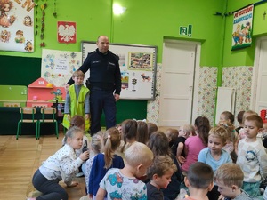 Dzielnicowy stoi obok ucznia który m założoną kamizelke odblaskową