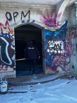 Policjant kontroluje pustostan pod kątem osób znajdujących się w potrzebie