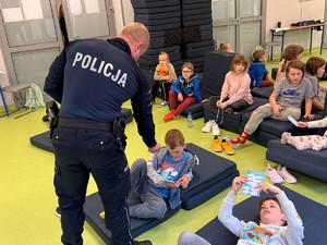 policjant wręcza dzieciom odblaskowe opaski