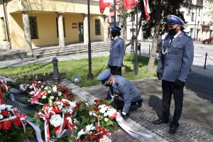 Komendant Powiatowy Policji w Wieliczce składa kwiaty. obok aystujący policjancji