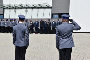 Policjanci oddają honor. W tle samorzadowcy odznaczeni medalami