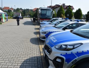 radiowozy policyjne. Za nimi autobus mobilny