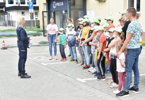 Policjantka wraz z osobami uczestniczacymi w wycieczce przed budynkiem komendy