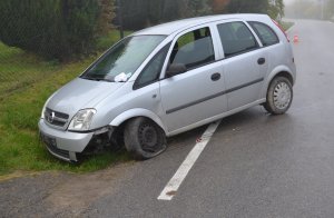 samochód częściowo w rowie,  z przebitą przednią oponą