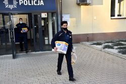 Policjantka niesie paczki do pojazdu